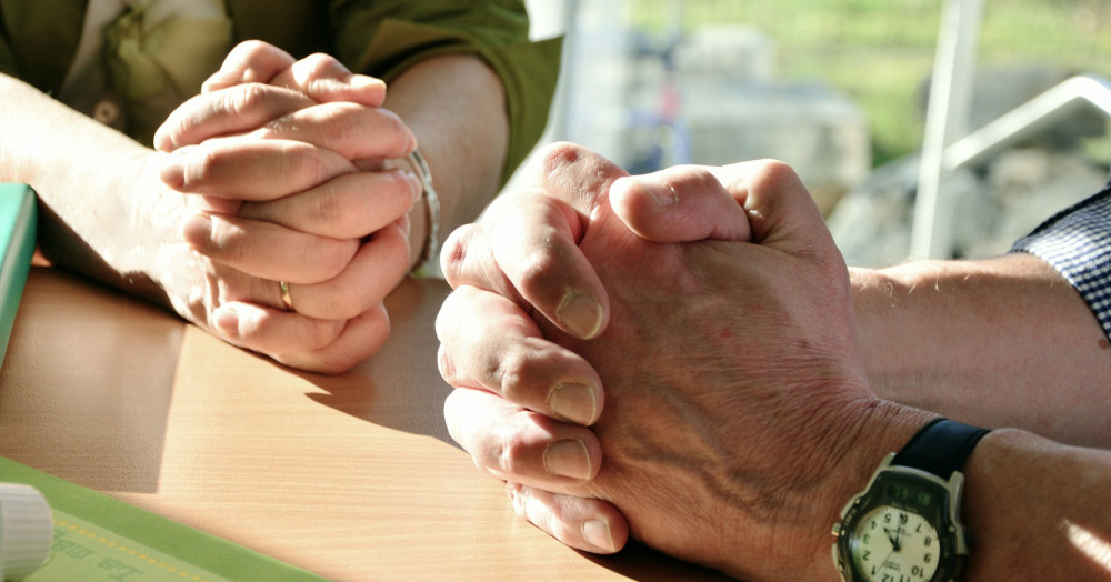A picture of two pairs of hands in prayer
