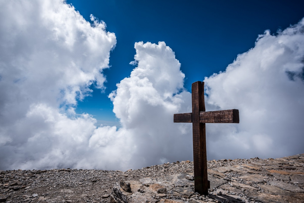 A photo of a cross against a blue sky with clouds